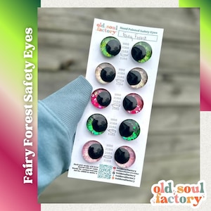 May include: A card of hand-painted Fairy Forest safety eyes from Old Soul Factory. The eyes are in various colors, including green, pink, and white, with black pupils. The card includes measurements of 16mm, 20mm, 25mm, and 35mm.