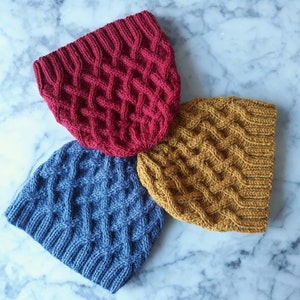 May include: Three knitted hats in different colors: red, blue, and yellow. Each hat has a cable knit pattern.