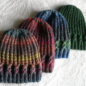 May include: Four knitted hats in different colors and patterns. The hats are made with a cable stitch and have a ribbed brim.