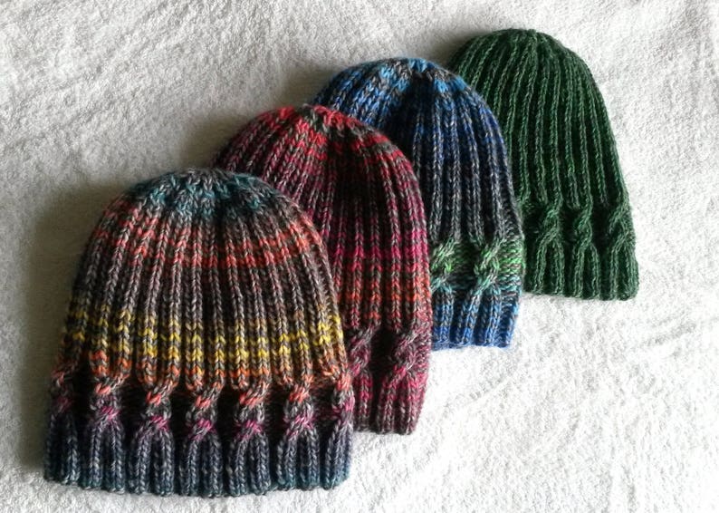 May include: Four knitted hats in different colors and patterns. The hats are made with a cable stitch and have a ribbed brim.