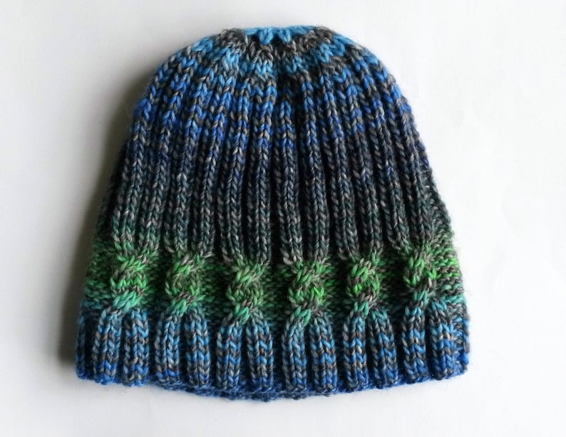 May include: A blue, green, and gray knitted hat with a cable knit pattern.