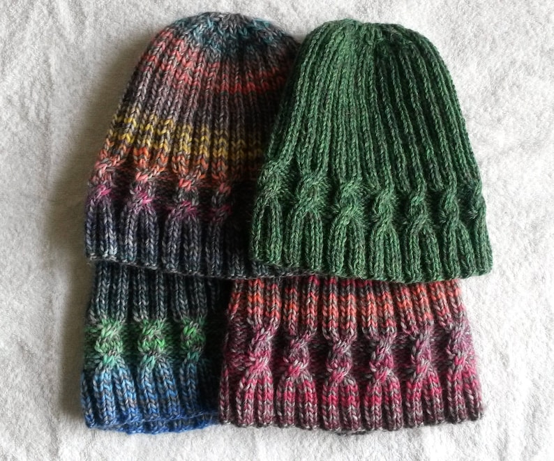 May include: Three knitted hats in different colors and patterns. The top hat is green, the middle hat is a rainbow ombre, and the bottom hat is a dark red ombre.