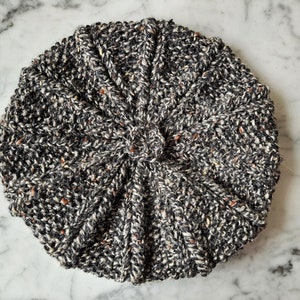 K&ouml;nnte beinhalten: Eine schwarze und wei&szlig;e Strickm&uuml;tze mit einem strukturierten Muster. Die M&uuml;tze ist aus einem weichen, warmen Material gefertigt und hat einen klassischen Stil.