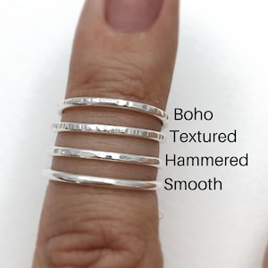 May include: Four silver stacking rings with different textures: smooth, hammered, textured, and boho.