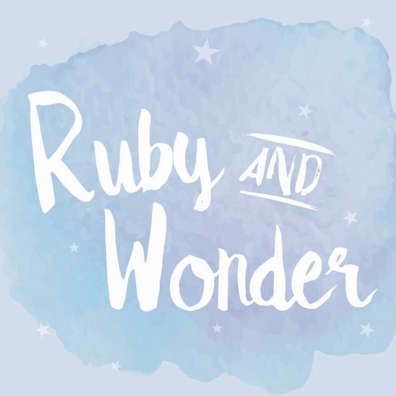 May include: A light blue watercolour background with white script text reading "Ruby AND Wonder". The design includes small white stars. The words are in a handwritten style.