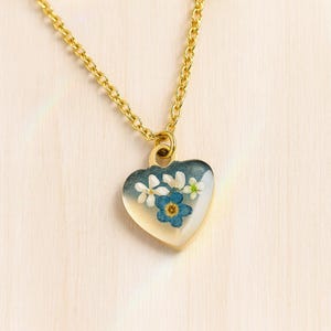 本物の花をあしらったマイクロハートペンダントネックレス。樹脂に閉じ込めた忘れな草のオパールフレーク。スチールチェーンと忘れな草の花のジュエリー。