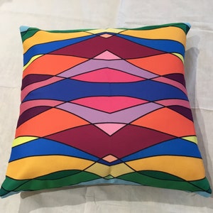 Puede incluir: Una almohada colorida con un patrón geométrico de ondas superpuestas en tonos de verde, azul, amarillo, naranja, rosa y morado.