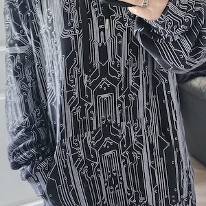 Könnte beinhalten: Schwarzer Kapuzenpullover mit weißem Leiterplattenmuster. Der Hoodie hat eine Kapuze mit Kordelzug und eine Vordertasche. Das Schaltungsdesign bedeckt den gesamten Hoodie.