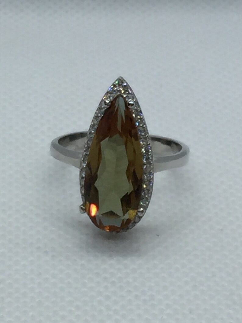 A silver ring with Natural Turkish Color Change Diaspore and a lot of small zirconia stones around it 925 Sterling Silver rhodium plated
