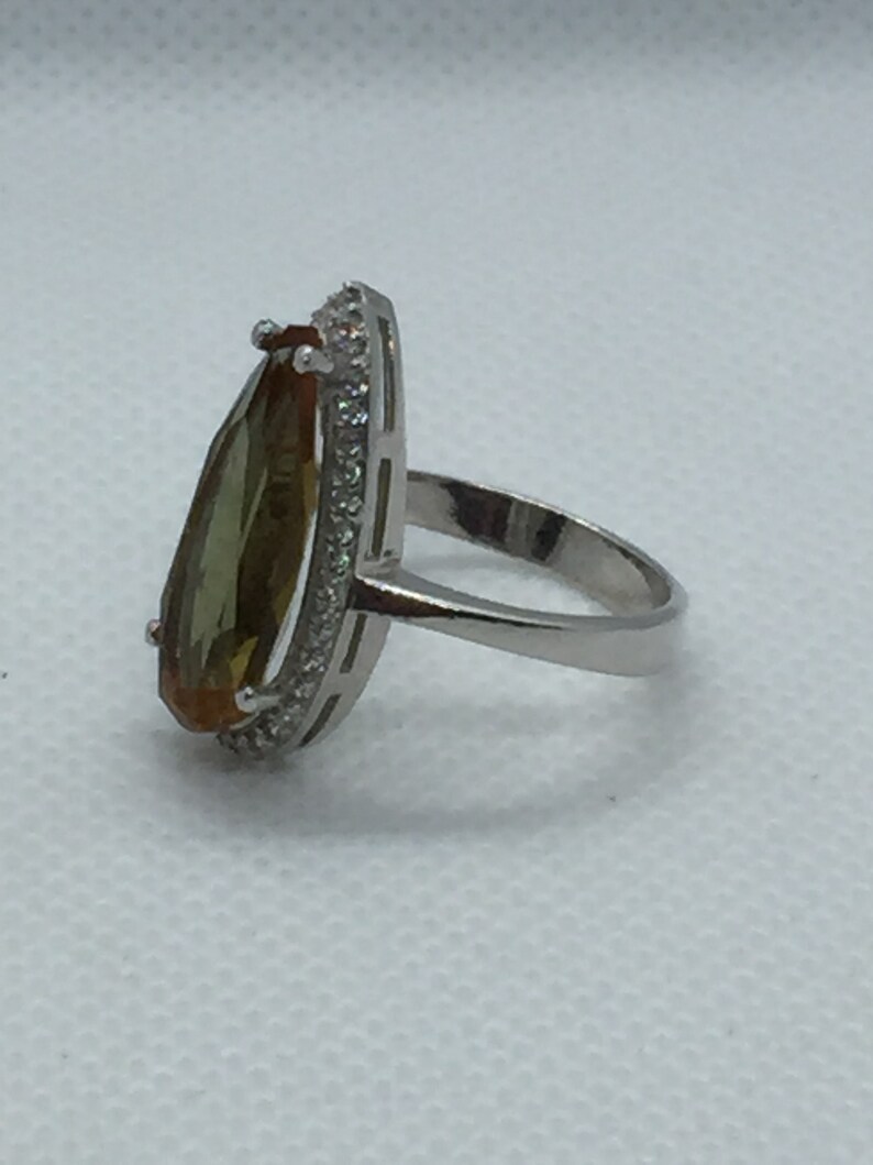 A silver ring with Natural Turkish Color Change Diaspore and a lot of small zirconia stones around it 925 Sterling Silver rhodium plated