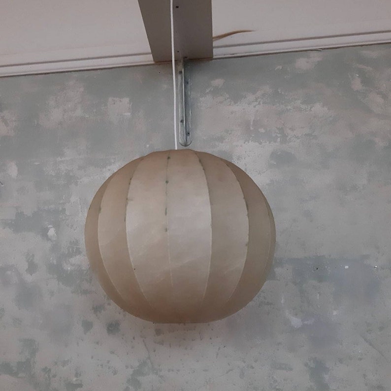 May include: A white, round, hanging lampshade with a pleated design.