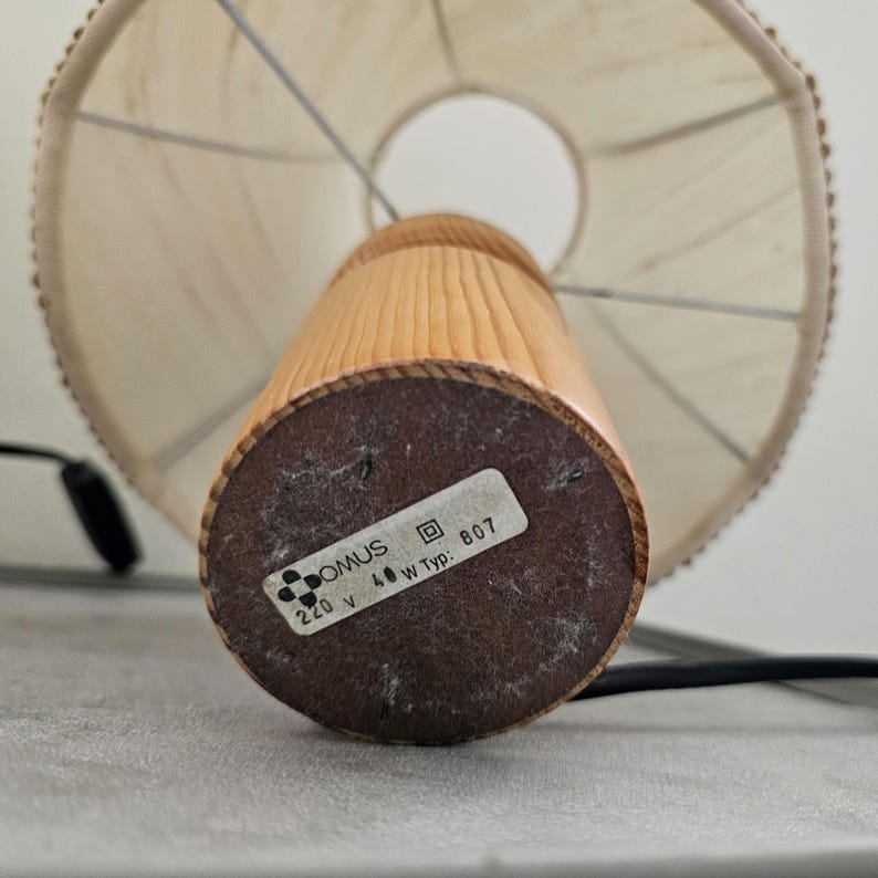 Pu&ograve; includere: Una lampada da tavolo in legno con un paralume bianco. La base della lampada ha un'etichetta che recita "DOMUS 220 V 40 W Typ. 807".