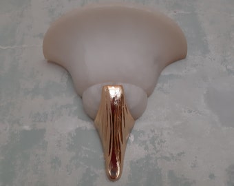 May include: A white wall-mounted light fixture with a curved, frosted glass shade and a gold-colored metal base.