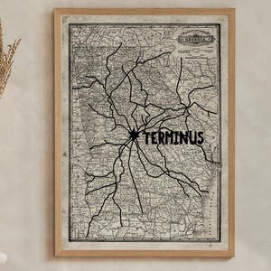 May include: A framed vintage-style map print featuring a network of black lines over a beige background with the word TERMINUS printed in bold black letters near the center. The map is displayed in a light wood frame on a neutral-colored wall.