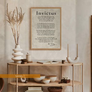 a framed quote of Invictus, a famous Roman soldier, displayed on a wall above a wooden shelf with various decorative items such as a vase, candles, and bowls.