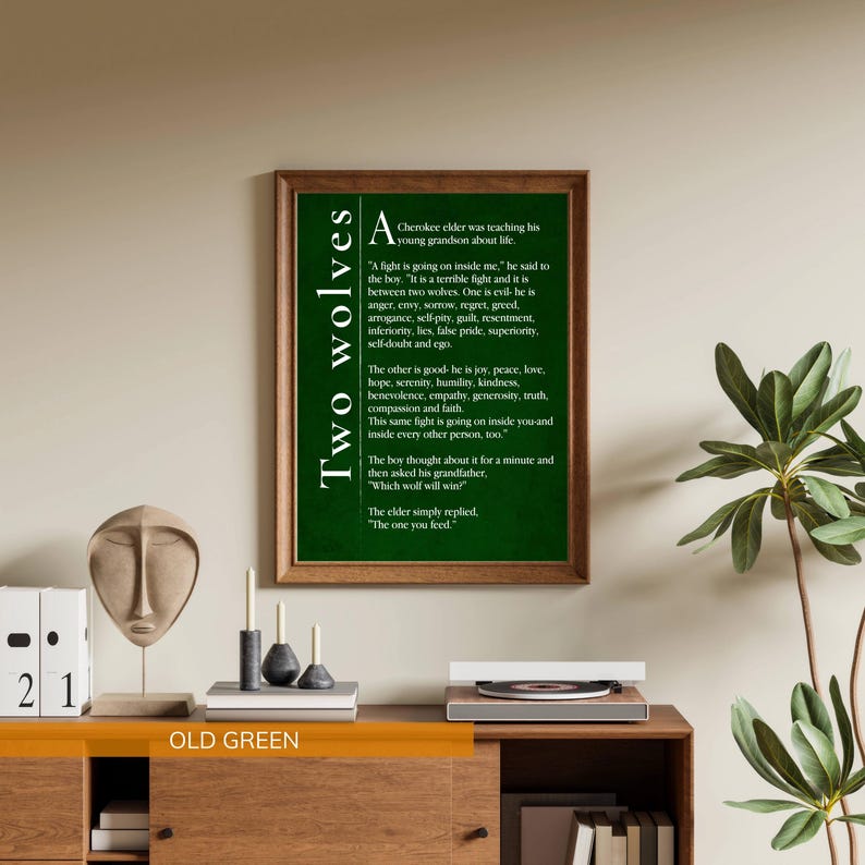 a framed poster of the poem "Two Wolves" by Carl Sandburg, which is hanging on a wall above a wooden dresser. The dresser has various items on it, including a small sculpture, candles, and books. There is also a potted plant in the background.