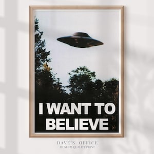 May include: Framed print featuring a vintage-style image of a flying saucer hovering above a treeline. Bold white text at the bottom reads "I WANT TO BELIEVE". The print is in a light wood frame, with the text "DAVE'S OFFICE MUSEUM QUALITY PRINT" at the bottom.