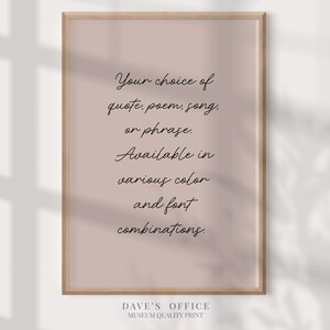 May include: A framed print with a light brown wooden frame. The print features text in a cursive font on a pink background. The text reads: "Your choice of quote, poem, song, or phrase. Available in various color and font combinations."
