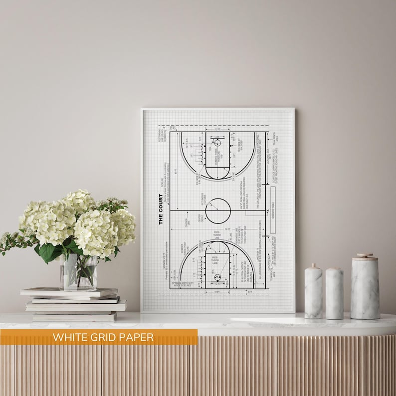 Op de afbeelding: Een zwart-wit afdruk van een basketbalveld-diagram op wit rasterpapier. De afdruk bevat de tekst "THE COURT" en veldafmetingen. De afdruk wordt weergegeven op een wit oppervlak met decoratieve items.
