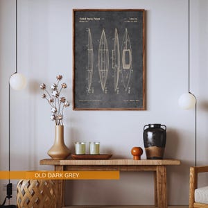 Puede incluir: Una impresi&oacute;n de arte mural enmarcada que presenta una ilustraci&oacute;n de patente de los Estados Unidos de un kayak sobre un fondo gris oscuro. El dibujo t&eacute;cnico muestra cuatro vistas distintas de la embarcaci&oacute;n etiquetadas Fig 1 a Fig 4.