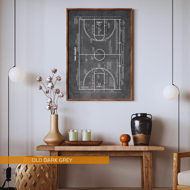 Op de afbeelding: Een ingelijste print van een basketbalveld diagram in wit op een donkergrijze achtergrond. De print is gelabeld "THE COURT" en wordt weergegeven boven een houten console met decoratieve items. De tekst "OLD DARK GREY" staat onderaan.
