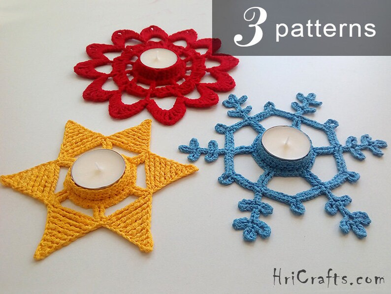 May include: Three crocheted candle holders in the shapes of a star, snowflake, and flower. The star is yellow, the snowflake is blue, and the flower is red. The candle holders are all made with a delicate crochet pattern.