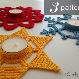 May include: Three crocheted candle holders in red, yellow, and blue. The holders are shaped like a flower, a star, and a snowflake. Each holder has a small, round opening in the center for a tea light candle.