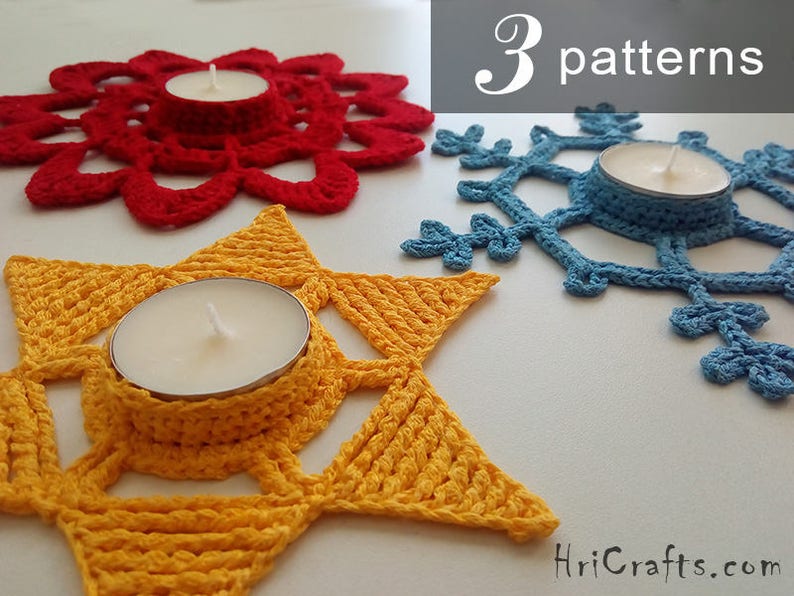 May include: Three crocheted candle holders in red, yellow, and blue. The holders are shaped like a flower, a star, and a snowflake. Each holder has a small, round opening in the center for a tea light candle.