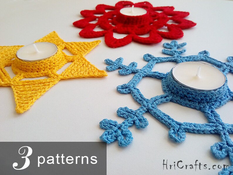 May include: Three crocheted candle holders in the shapes of a star, snowflake, and flower. The star is yellow, the snowflake is blue, and the flower is red. Each holder has a small, round indentation in the center to hold a tea light candle.