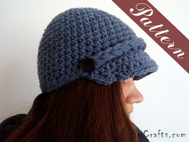 May include: A blue crocheted hat with a wide brim and a button detail. The hat is worn by a person with long brown hair.