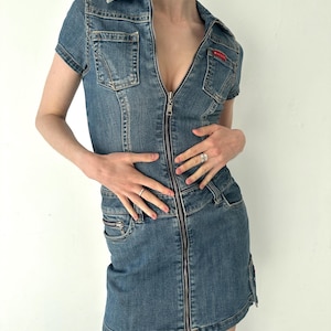 May include: A blue denim dress with a zipper down the front and short sleeves. The dress has a collared neckline and two pockets on the front.