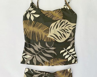 May include: A two-piece swimsuit with a green, brown, and white tropical leaf print. The top is a sleeveless tank style with a scoop neck. The bottom is a high-waisted bikini bottom.
