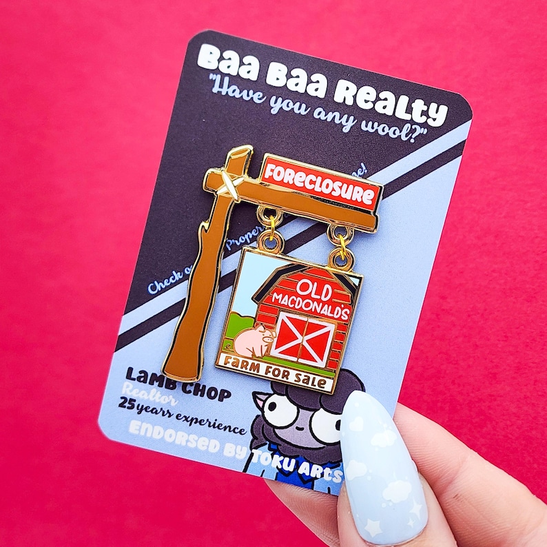 May include: A novelty pin featuring a sign that reads "FORECLOSURE" and "FARM FOR SALE." The pin has a barn design with a pig and the words "OLD MACDONALD'S." The pin is on a card that says "Baa Baa Realty" and "Lamb Chop Realtor."