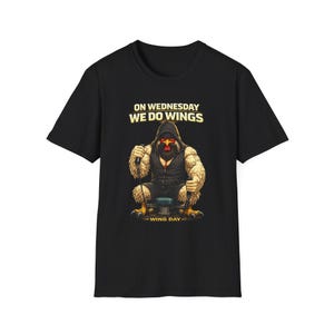 May include: Black t-shirt with a graphic of a chicken-like creature in a hoodie, holding a microphone. The text "ON WEDNESDAY WE DO WINGS" is above the image, and "-WING DAY-" is below.