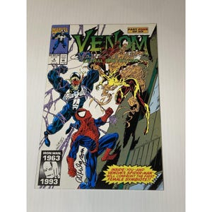 Op de afbeelding: Een stripboekcover voor "Venom: Lethal Protector" met Venom, Spider-Man en een vrouwelijke symbiote. De cover heeft een dynamische compositie met levendige kleuren en actieposes. Het Marvel Comics-logo is zichtbaar, samen met het nummer en de datum van de uitgave.