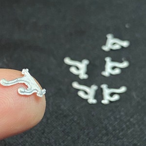 May include: A set of seven small, white, plastic, decorative, 3D printed ornaments. The ornaments are shaped like a stylized letter "S".