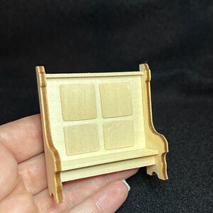 May include: A miniature wooden bench with a back and four square panels. The bench is made of light brown wood and has a natural finish.