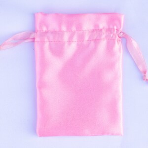 May include: A pink satin drawstring bag with a white cord.