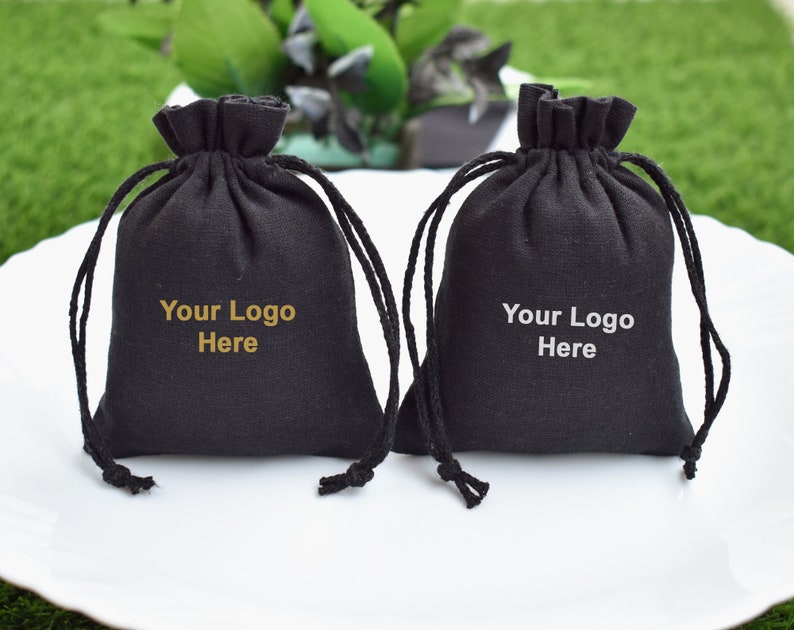 May include: Two black drawstring bags with a gold inscription that reads "Your Logo Here".