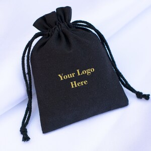 May include: Black drawstring bag with a gold inscription that reads "Your Logo Here".