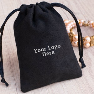 May include: Black velvet drawstring pouch with a white embroidered logo that says "Your Logo Here".