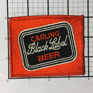 May include: An orange fabric patch with a black and white embroidered label that reads "Carling Black Label Beer".