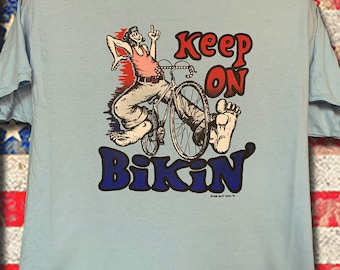 Keep on Bikin' Printed in the 70's this transfer never sold and stored away over 30 years. Printed on a LT Blue New 100% All Sizes Last FEW