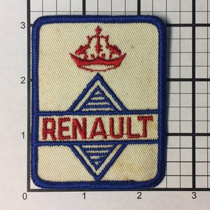 Op de afbeelding: Een witte geborduurde patch met een blauwe rand. De patch heeft een rode kroon met daaronder een blauwe ruit. Het woord "RENAULT" is geborduurd in rode letters.