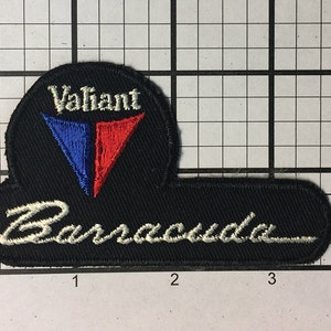 May include: Black and white embroidered patch with the words "Valiant Barracuda" in white. The patch features a red and blue triangle logo with the word "Valiant" in white.