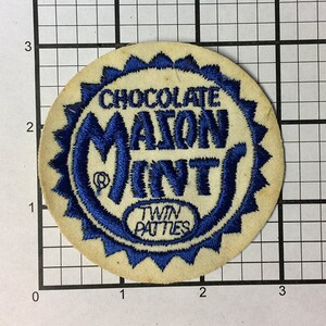 May include: A blue and white embroidered patch with the text "Chocolate M&M's Twin Patties".