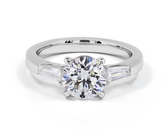 May include: A silver engagement ring with a round center diamond and two baguette diamonds on either side.
