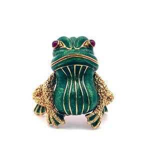 May include: A frog-shaped ring featuring a vibrant green enameled body with gold-toned accents and textured legs. The frog has two small, round, dark red stones set as eyes, with a smooth, glossy finish on the green enamel and a detailed, textured surface on the gold-toned limbs.