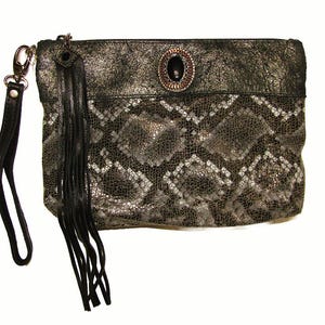May include: A rectangular clutch with a snakeskin pattern in shades of gray and black. The clutch features a black leather wrist strap, a decorative black tassel, and a decorative oval embellishment on the front.