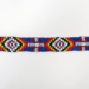 May include: A beaded bracelet with a geometric pattern in red, blue, yellow, white, and black.